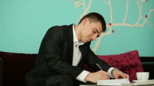 stock-footage-young-guy-writing-something-and-thinking-with-a-smile