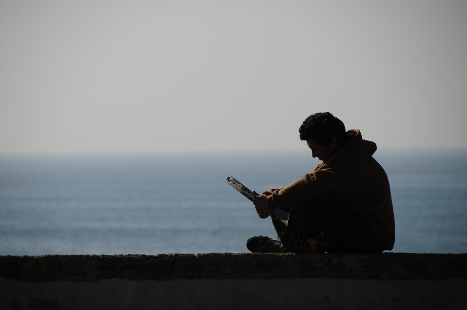 “Silhouette of a man reading by the ocean” (Kamil Porembiński/Creative Commons)
